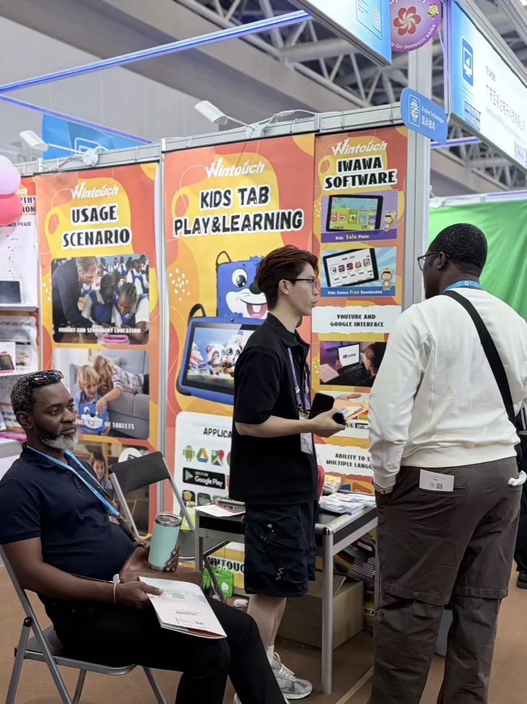 Wintouch staff demonstrating a kids tablet to an African buyer at Canton Fair 2026
